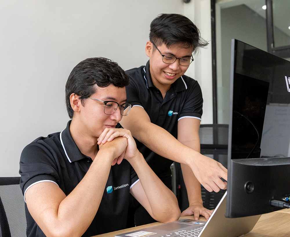 Zetamotion Employees Two Zetamotion engineers collaborating on a laptop during AI-powered quality control project development.