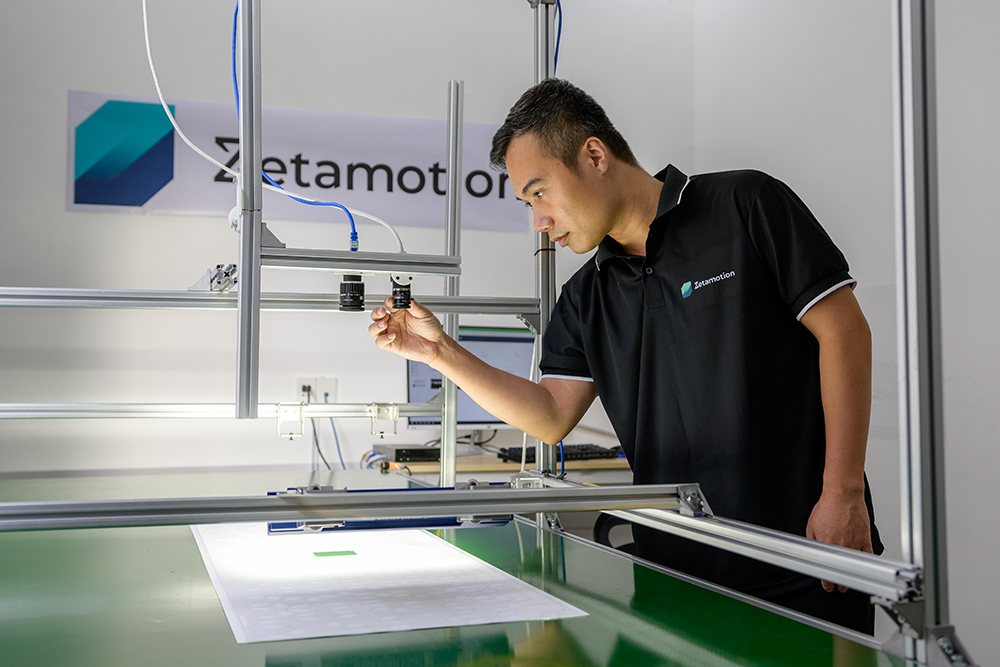 Inspecting Inspection Station Technician inspecting a camera module on an AI-powered quality control machine at Zetamotion lab.